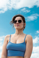 Beautiful young brunette in sunglasses against the sky