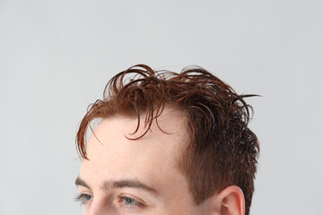 Obraz premium Young man with wet hair on light background