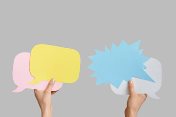 Female hands with speech bubbles on grey background