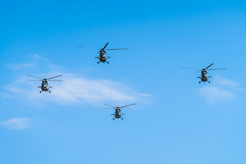 Four helicopters flying in formation against a clear blue sky