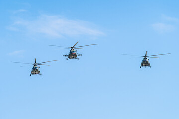 Military helicopters conducting a coordinated flight under a clear blue sky