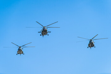 Helicopters flying in formation against a clear blue sky during daylight