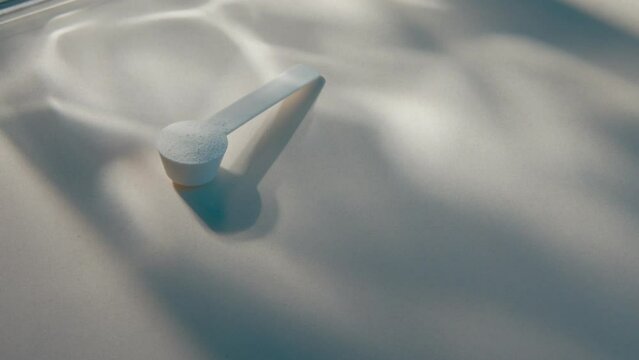 Sport supplement, creatine, hmb, bcaa, amino acid or vitamin measure with powder in a lifestyle contest. 4k high quality video. Sport nutrition health and food concept. Dry flowers, stones and shadows