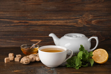 Cup of ginger tea and bowl with honey on wooden background