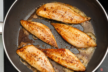 Small fish fillet fried in a frying pan. Cooking fish without oil. View from above.