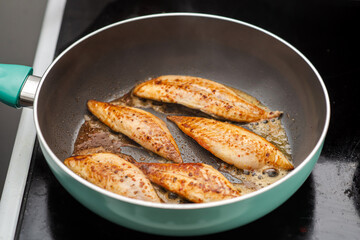 Small fish fillet fried in a frying pan. Cooking fish without oil.