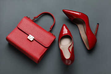 Stylish red high heels and handbag on grey background