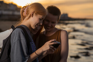 Three women look at photos on a camera in the evening