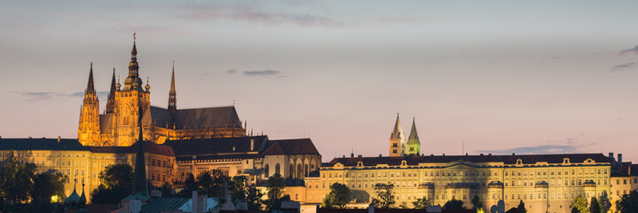 Night time view of Prague Castle with St. Vitus Cathedral and St. George's Basilica lit up on the hilltop above Old Town Prague