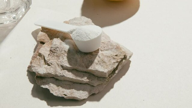 Sport supplement, creatine, hmb, bcaa, amino acid or vitamin measure with powder in a lifestyle contest. 4k high quality video. Sport nutrition health and food concept. Dry flowers, stones and shadows