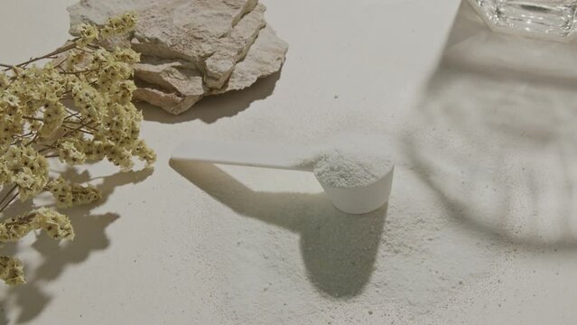 Sport supplement, creatine, hmb, bcaa, amino acid or vitamin measure with powder in a lifestyle contest. 4k high quality video. Sport nutrition health and food concept. Dry flowers, stones and shadows