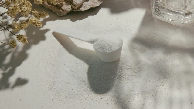 Sport supplement, creatine, hmb, bcaa, amino acid or vitamin measure with powder in a lifestyle contest. 4k high quality video. Sport nutrition health and food concept. Dry flowers, stones and shadows