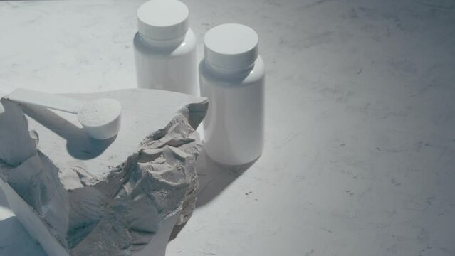 Sport supplement, creatine, hmb, bcaa, amino acid or vitamin measure with powder in a lifestyle contest. 4k high quality video. Sport nutrition health and food concept. Dry flowers, stones and shadows