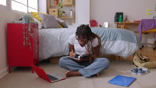 Millennial female college student with vitiligo doing homework in her room. Education and e-learning concept.