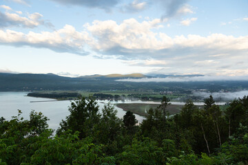 Fototapeta na wymiar High angle view of Baie-Saint-Paul valley under low fog and the St. Lawrence River seen from point of view during a beautiful summer morning, Charlevoix, Quebec, Canada 