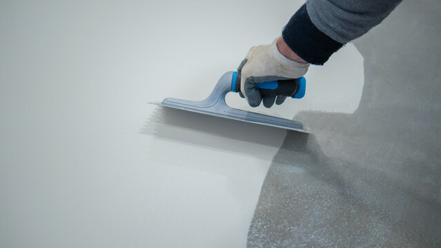 A construction worker renovates the balcony floor and spreads waterproof polyurethane resin and glue before sealing it
