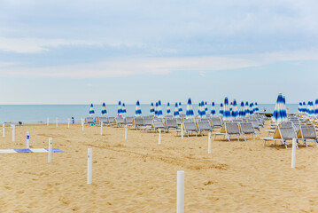 In the morning, by the sea, empty sun loungers, chairs and locked umbrellas on the beach.