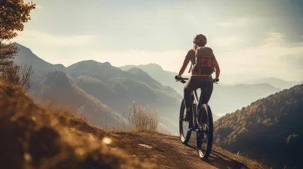 Tuinposter Young woman riding bicycle on beautiful mountain trail in morning © Fred