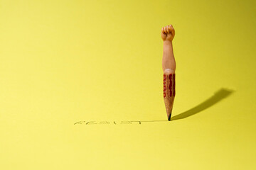 Surreal abstract scene with an old wooden pencil from where comes out a human hand with a fist...