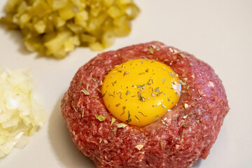 Fresh delicious beef tartare served with a raw egg, cut onions and pickles, raw meat dish macro,...
