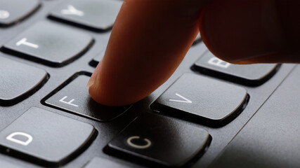 Man pressing the letter F key on a simple laptop computer keyboard, object, finger macro, detail,...