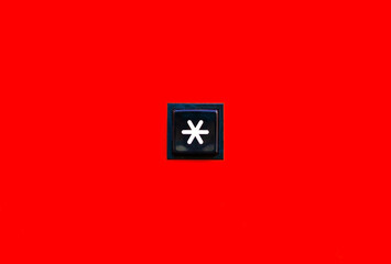 One single asterisk symbol star sign square button key on bright red background abstract scene, object top view, closeup. Star special symbol *, isolated. Password, unknown letter, character concept