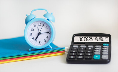 On a light background - an alarm clock, folders and a calculator with the inscription NOTARY PUBLIC.