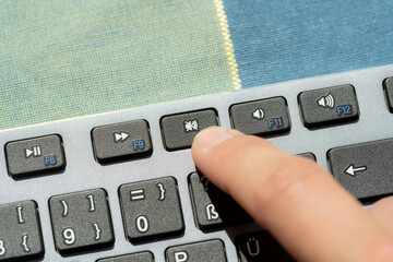 Anonymous man pressing the mute button, sound off key on a modern computer keyboard, hand, finger...