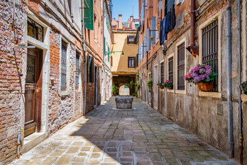 Fototapeta na wymiar Narrow pedestrian cobblestone old alleys in Venice, Italy. Old worn out medieval buildings.