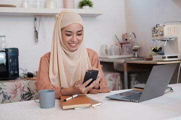 Young pretty modern muslim woman in hijab working on laptop in office room, education online,...