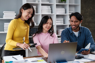 Group of young Asian business people brainstorming, looking at laptop computer.