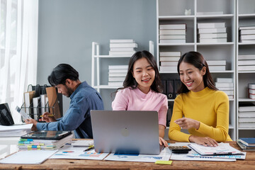 Group of young Asian business people brainstorming, looking at laptop computer.