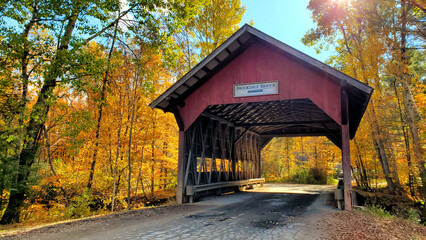 Red, wooden, covered Brookdale bridge with beautiful autumn colors, Stowe, Vermont, USA