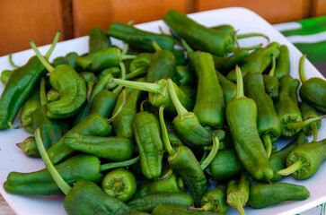 Green peppers on a plate on a wooden background
