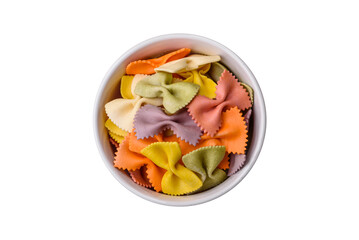 Raw farfalle pasta in different colors on a dark concrete background