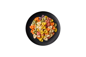 Raw farfalle pasta in different colors on a dark concrete background
