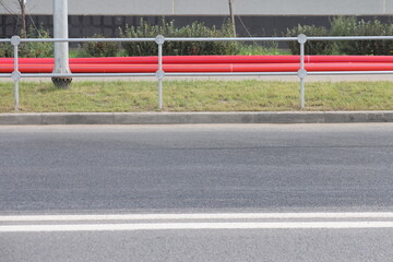 A street border painted white and blue against a road and green foliage in a summer close-up. Road safety, minimalism.