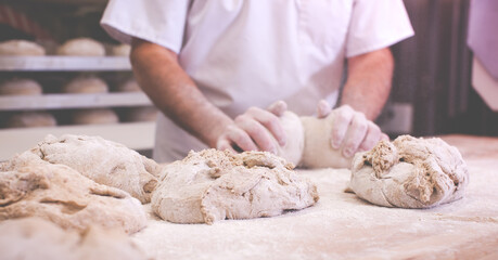 close-up on hands of baker in bakery kneading dough to bake fresh bread in the morning