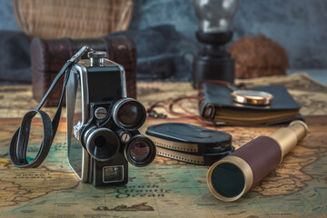 Vintage film camera with cassettes and spyglass on an old nautical map. Close-up