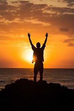 a happy man waving his hands in air in against sunset