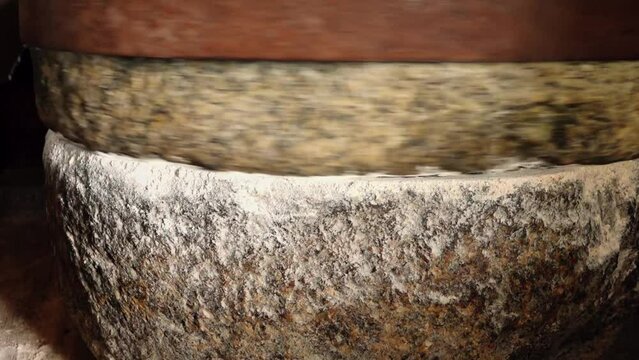 Grinding rye grain with ancient stones. Bread Day in Latvia. Honoring the bread on the table. Honoring the ancient traditions of baking bread.