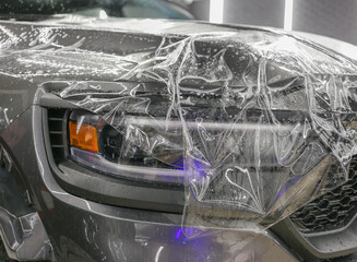 A car wrapping specialist applies a polyurethane film to the car. Selective focus. PPF protective film against chips and scratches. Car wrapping. 