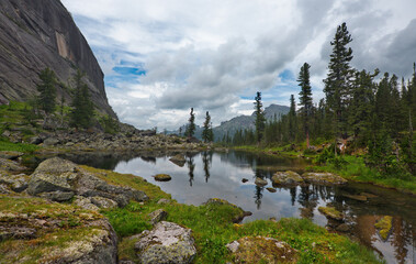 Russia. South of Siberia. Western Sayan. Panoramic view of a high-altitude lake surrounded by harsh rocks from a mountain pass in the Ergaki Natural Mountain Park.