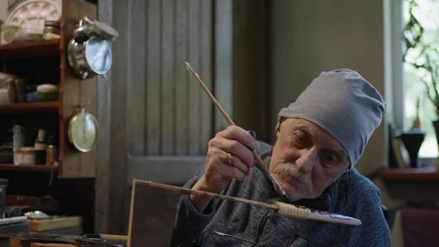 Elderly male master works in his workshop restoring japanese deba knife sheath