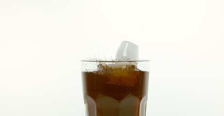 Ice Cubes Falling into Glass of Coke against White Background