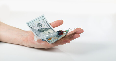 Syringe Falling into Hand with Dollars against White Background