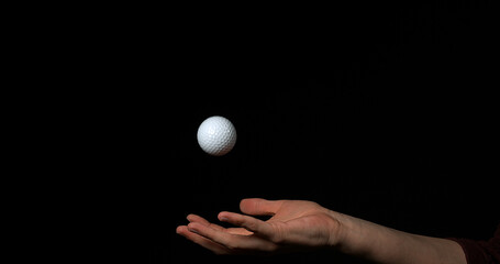 Fototapeta na wymiar Hand of Woman Throwing a Ball of Golf against Black Background