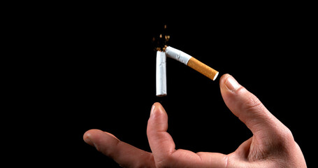 Hand of Man who breaks a Cigarette on Black Background