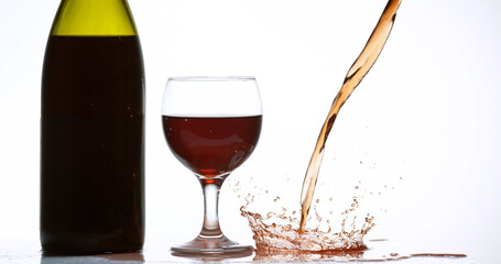 Red Wine being poured into Glass, against White Background