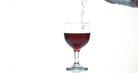 Red Wine being poured into Glass, against White Background
